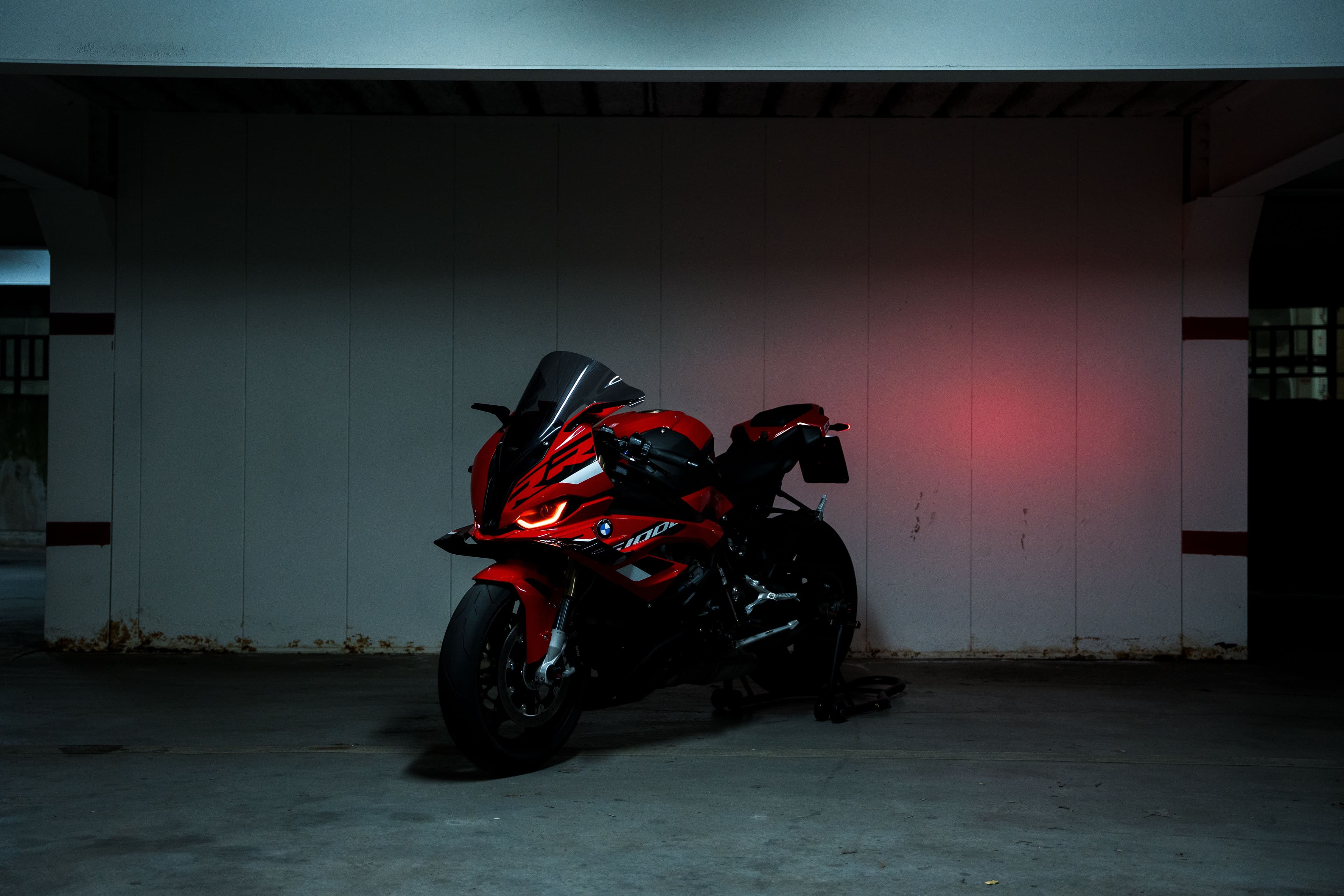 Moto sportive rouge à l'arrêt, éclairage rasant
