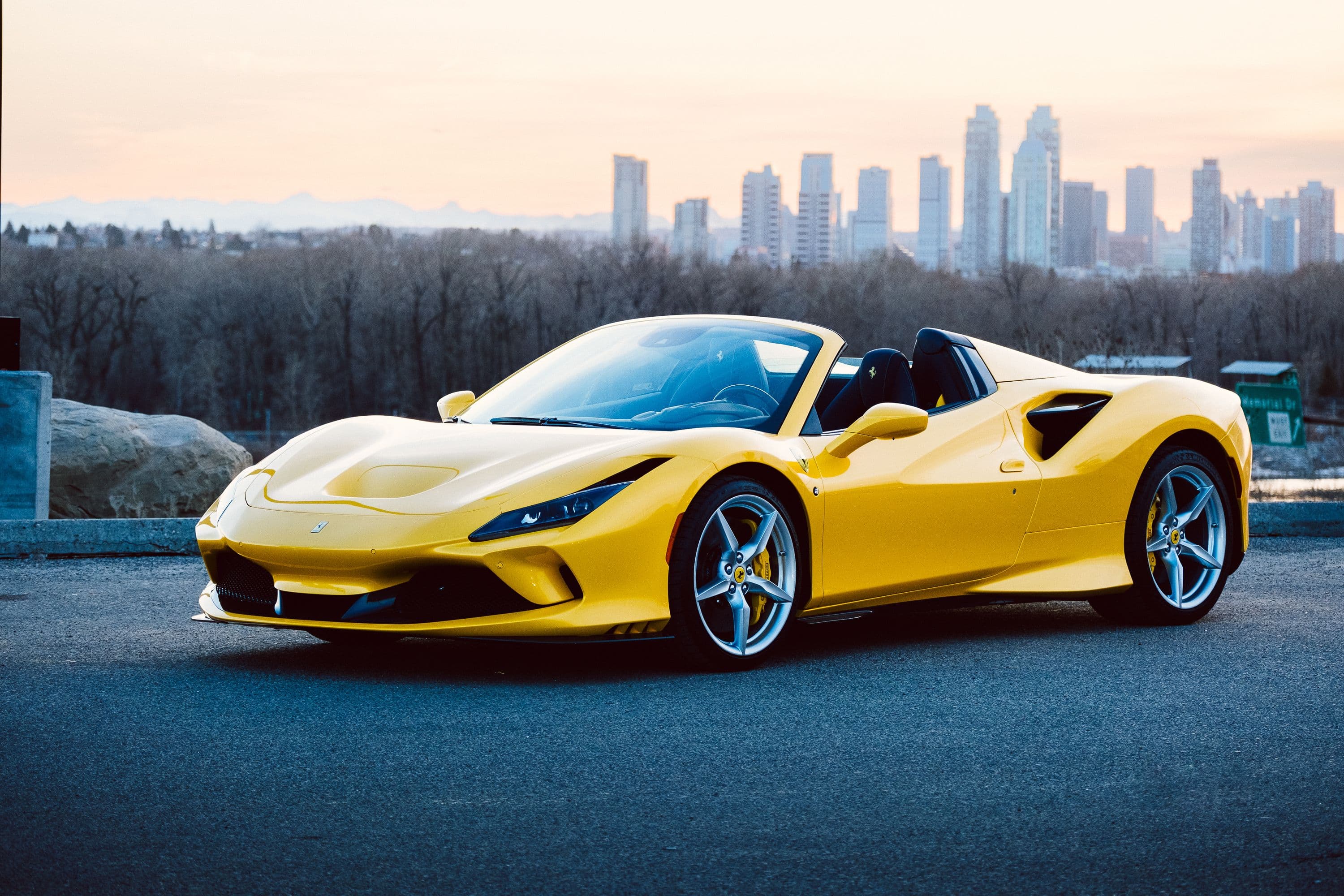 Coupé sportif décapotable jaune, au crépuscule devant une skyline